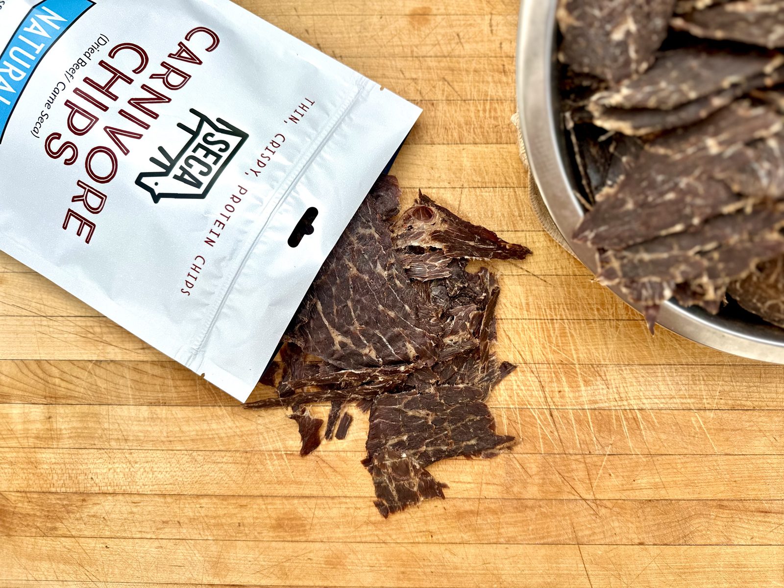 SECA Carnivore Chips 2oz On-the-Go bag with crispy carnivore chips on a wooden board